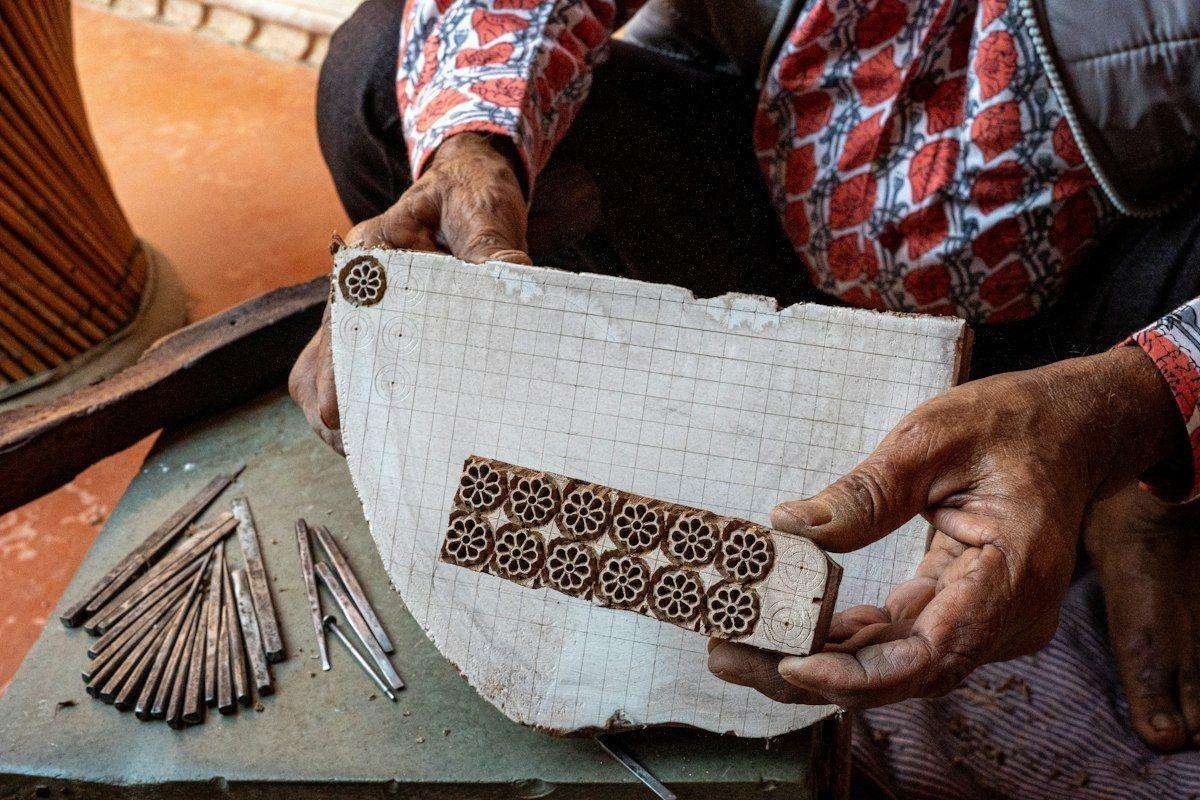 Illustrative image: artisan holding a wooden printing block over fabric