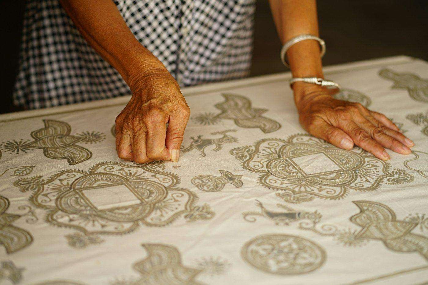 Illustrative image: hands block printing a pattern on fabric