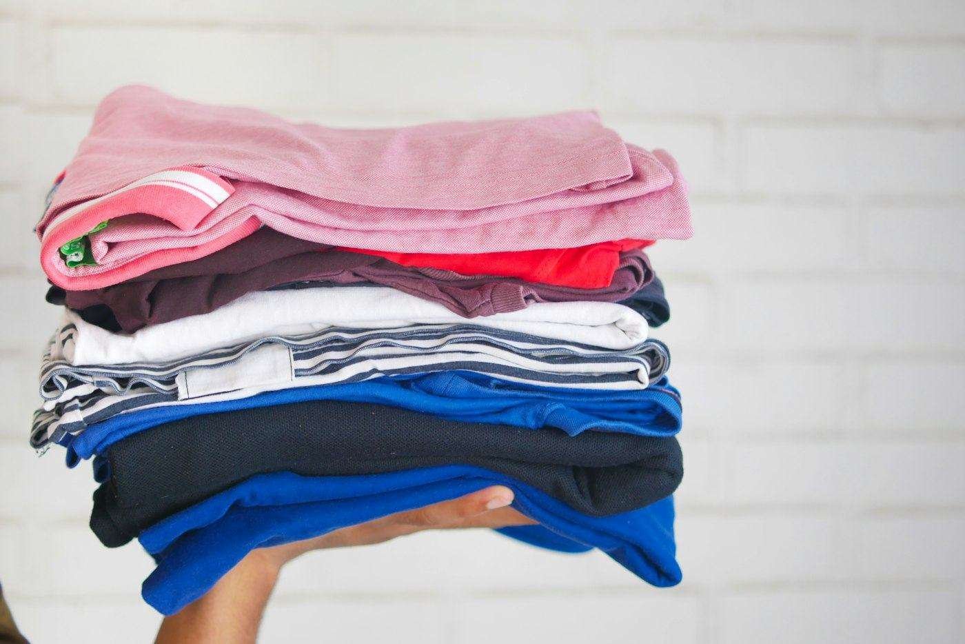 Illustrative image: hand holding a stack of folded clothes
