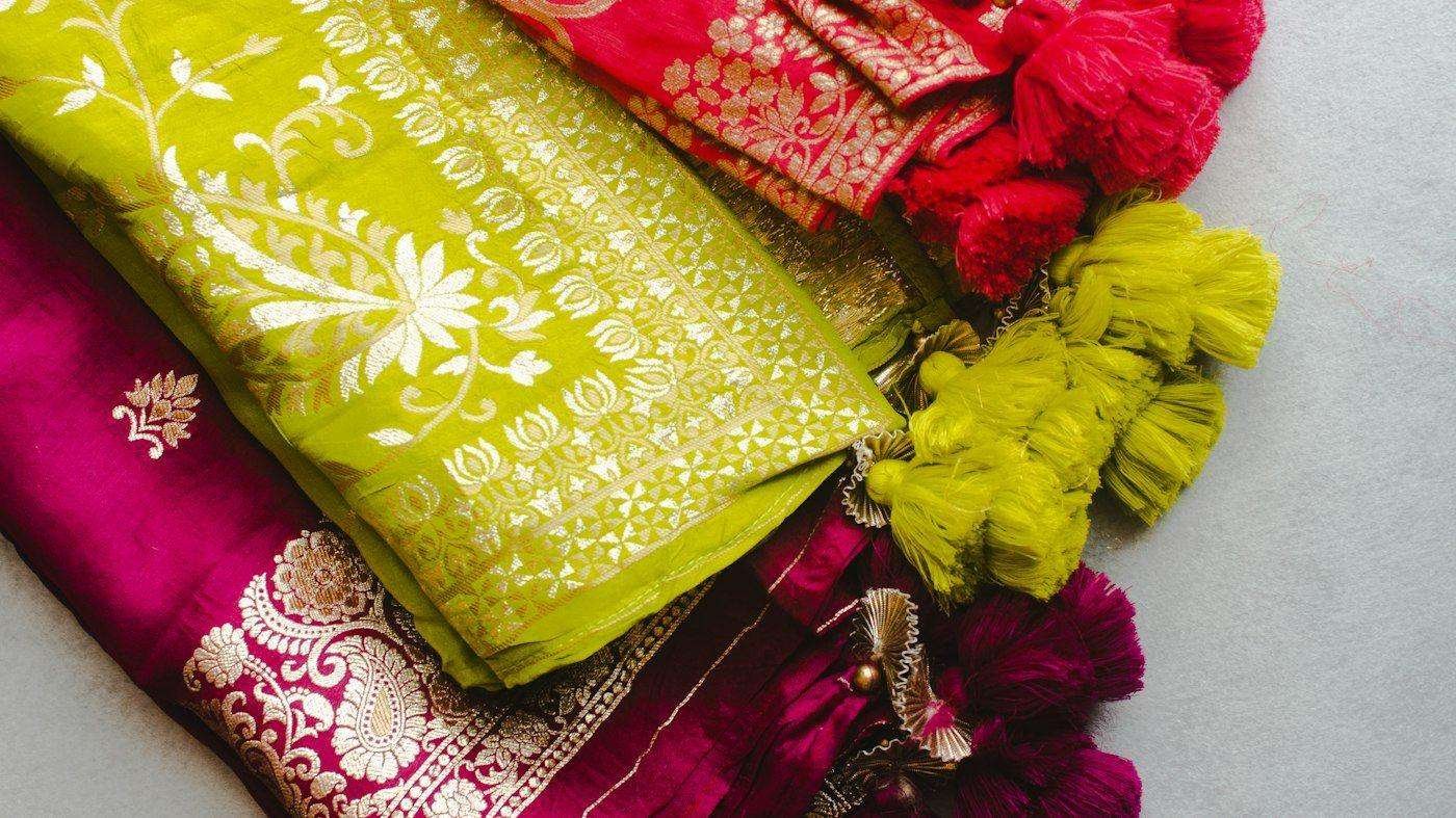 Illustrative image: folded sarees and printed fabrics on a table
