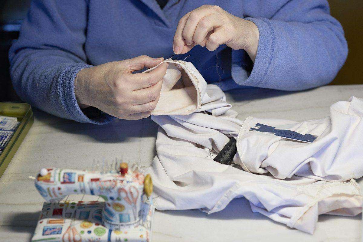 Illustrative image: hands stitching fabric with needle and thread