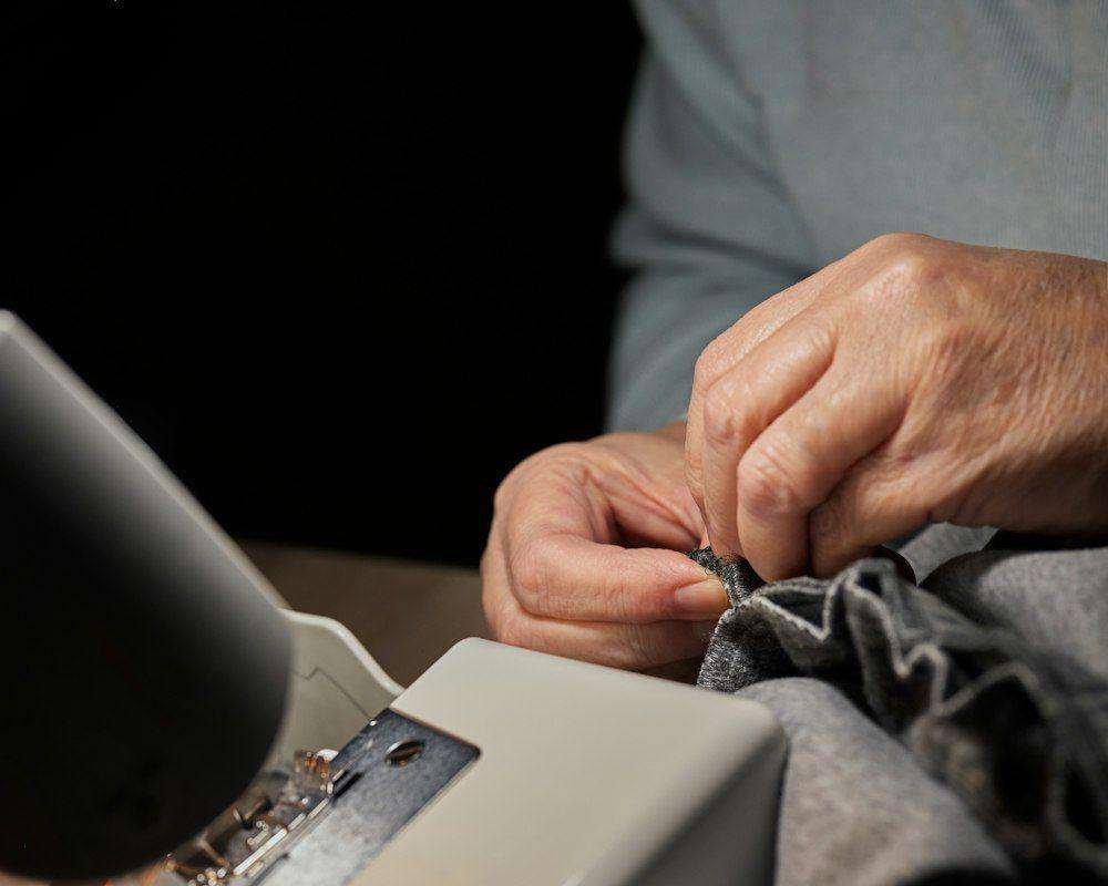 Illustrative image: hands sewing fabric on a sewing machine