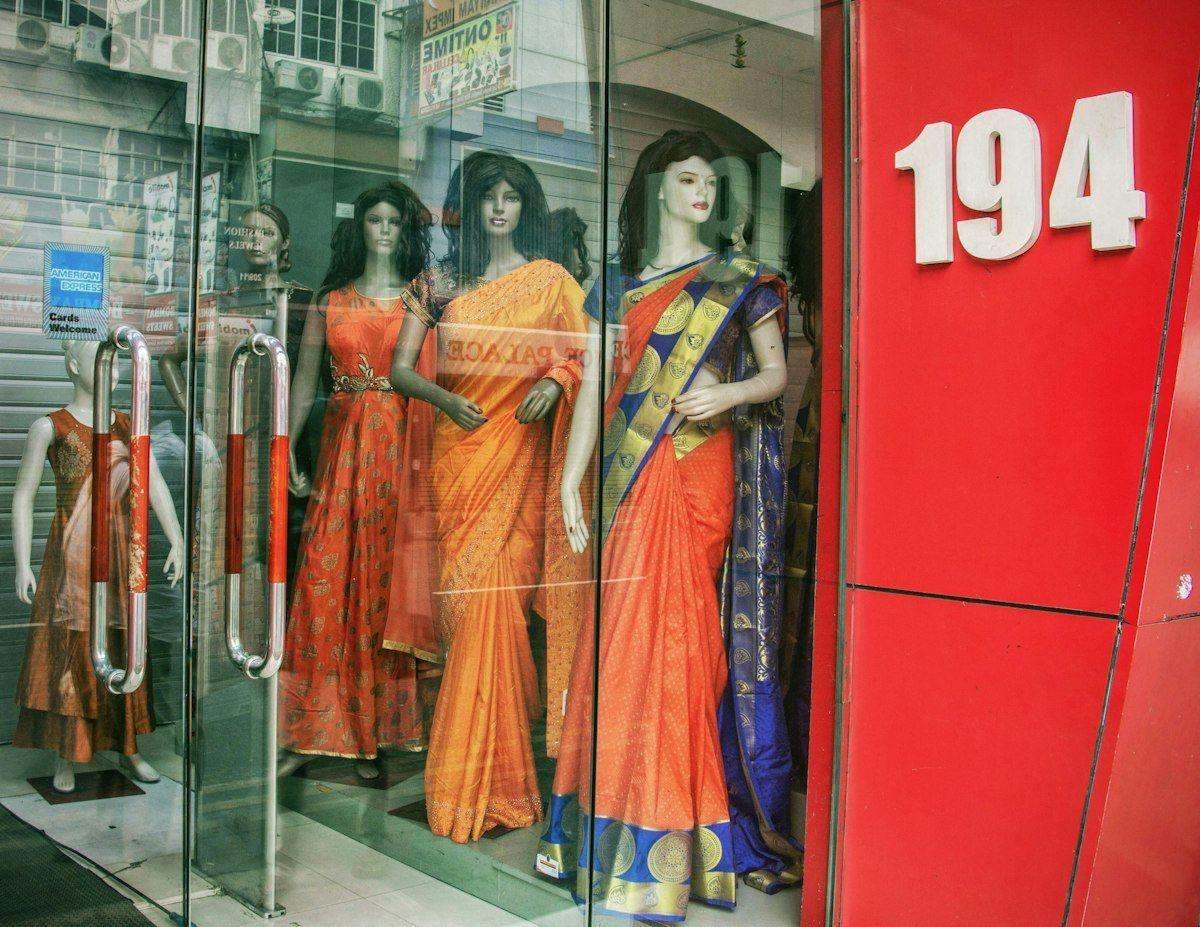 Illustrative image: sarees displayed on mannequins in a shop window