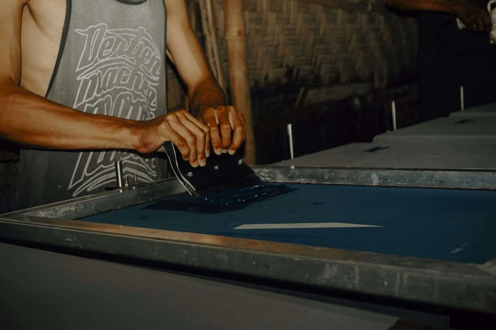 Illustrative image: hands screen printing on a print table