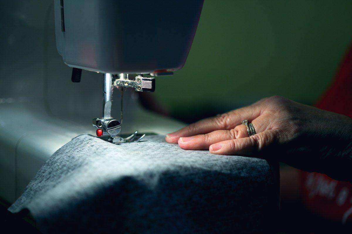 Illustrative image: hands guiding fabric through a sewing machine