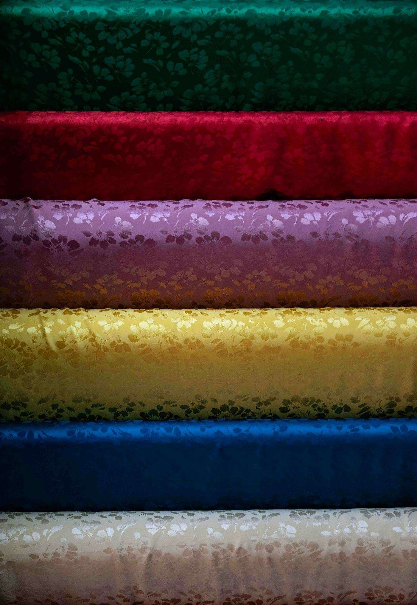 Illustrative image: rolls of fabric stacked in rich colours