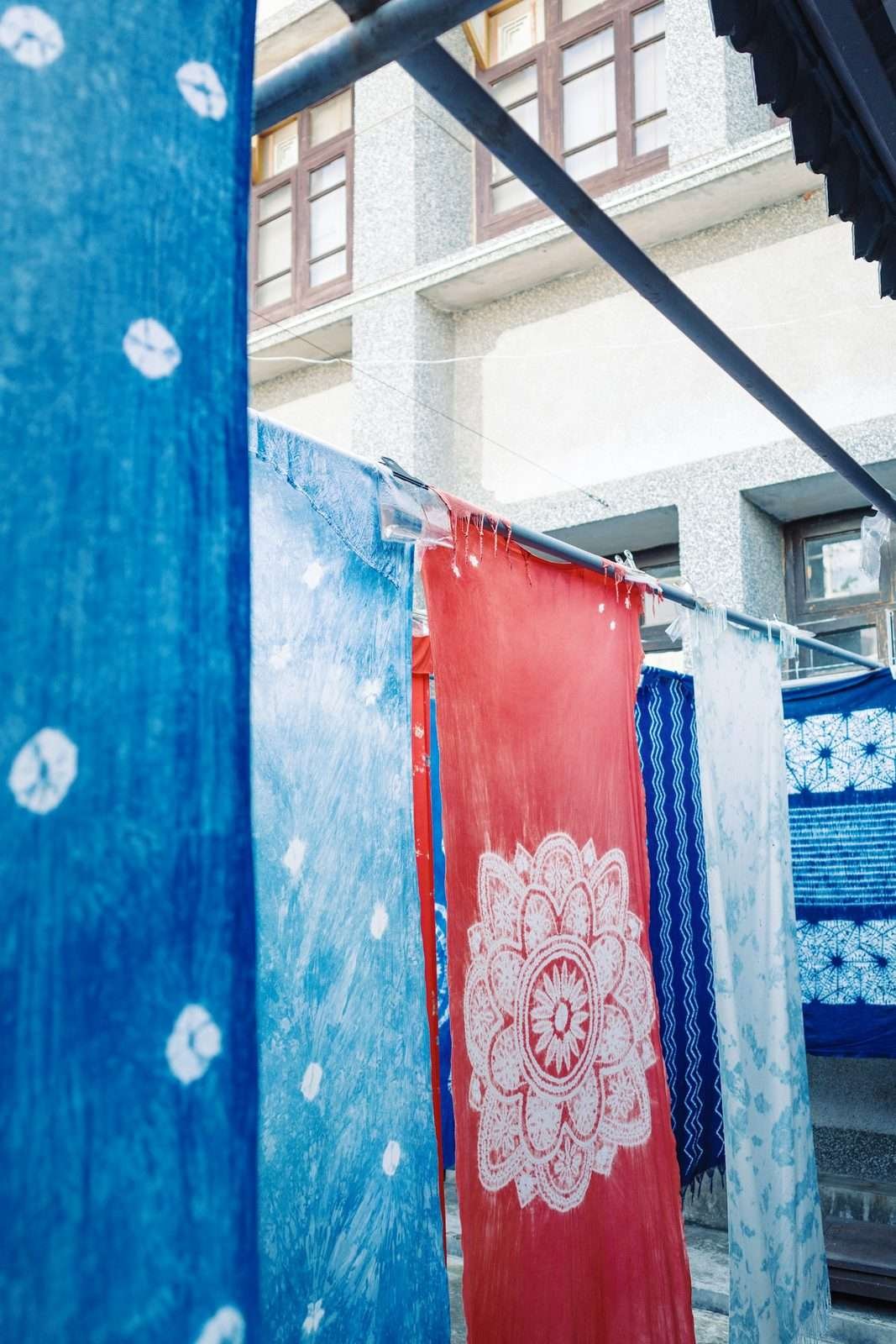Illustrative image: tie-dyed fabrics with white resist dots hanging outdoors
